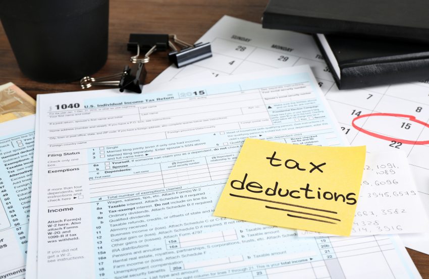 Tax forms with yellow sticky note with the words tax deductions