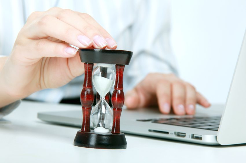 Person at laptop with hourglass on desk