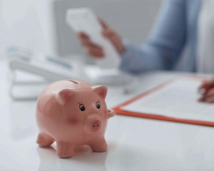 Piggy bank on desk with man holding calculator
